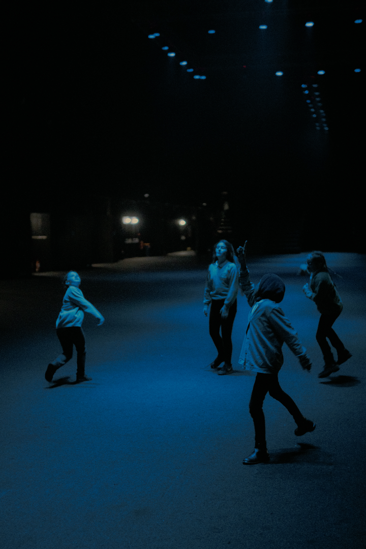 Children running underneath blue beams of light. Visitor by Christo Squier