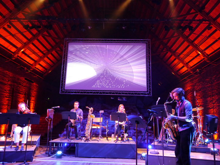 Subatomic by Christo Squier and Dr. Teppei Katori. A Concert with projections of subatomic particles at snape maltings concert hall.